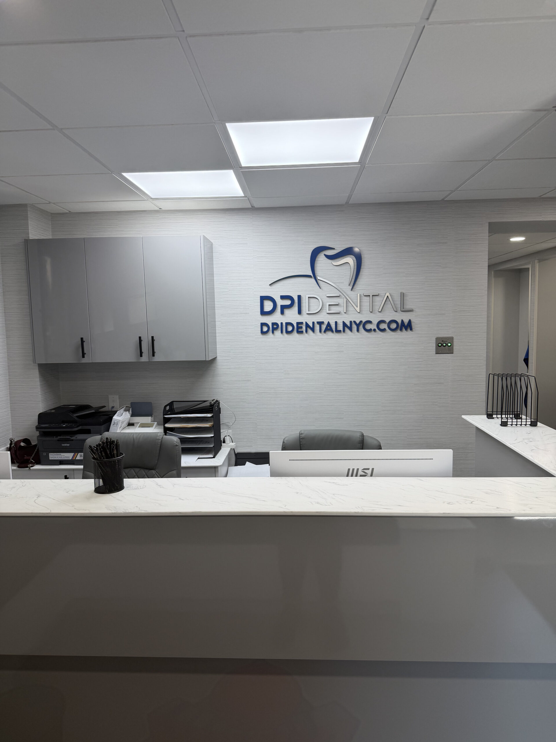 DPI Dental office reception desk with the DPI Dental logo on the wall
