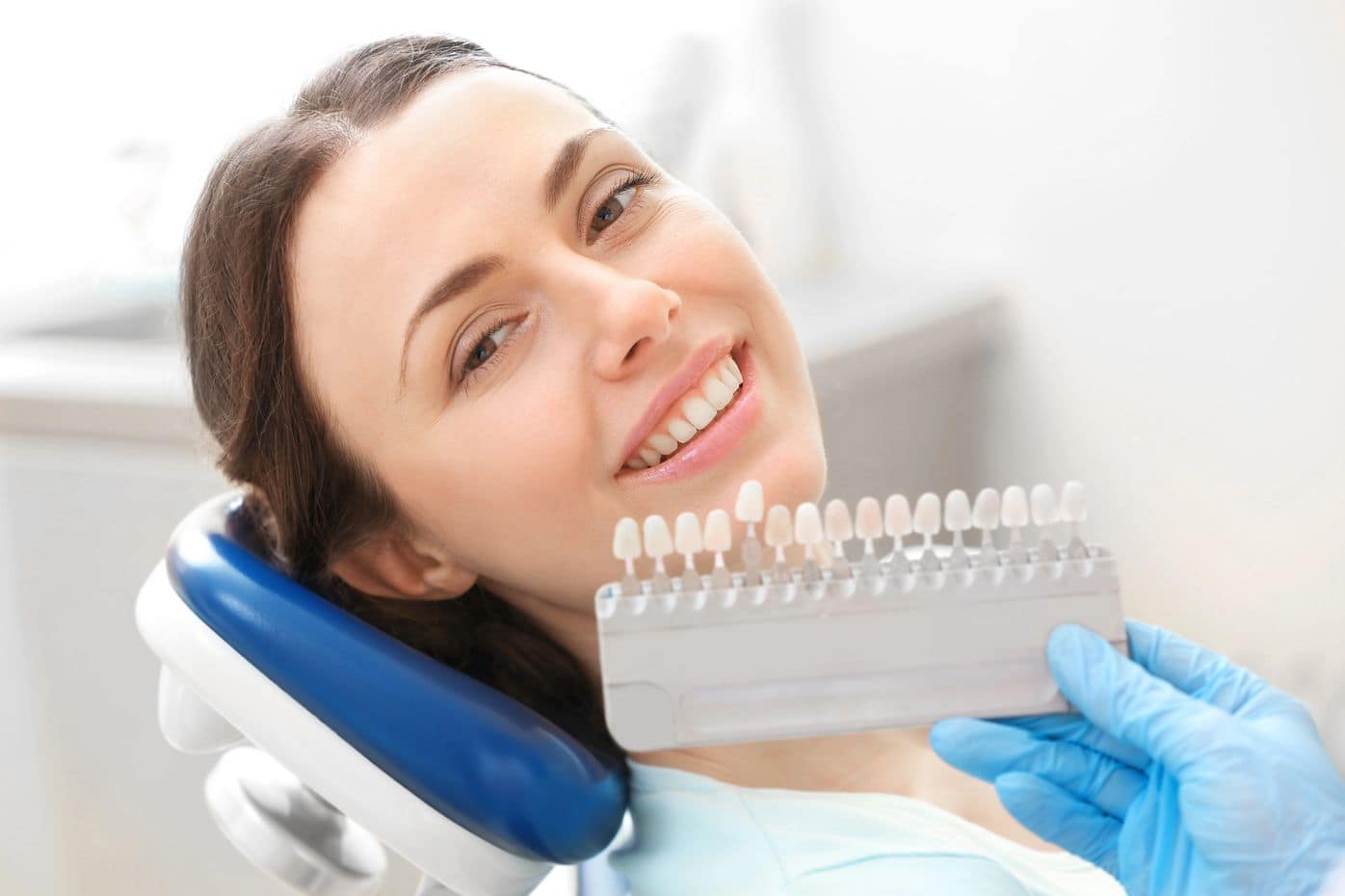 Dentist holding a tooth shade guide beside a smiling patient