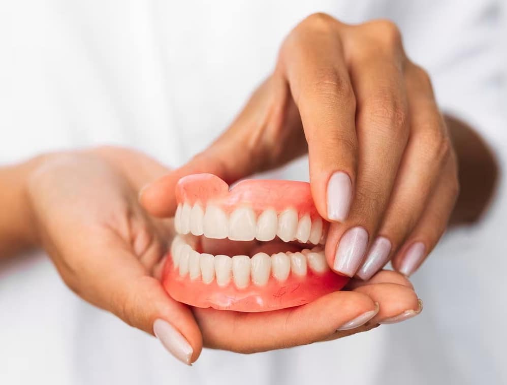 Hands holding a full set of dentures