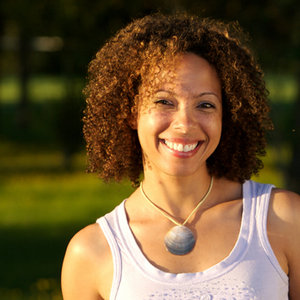 Smiling woman with curly hair standing outdoors in a park