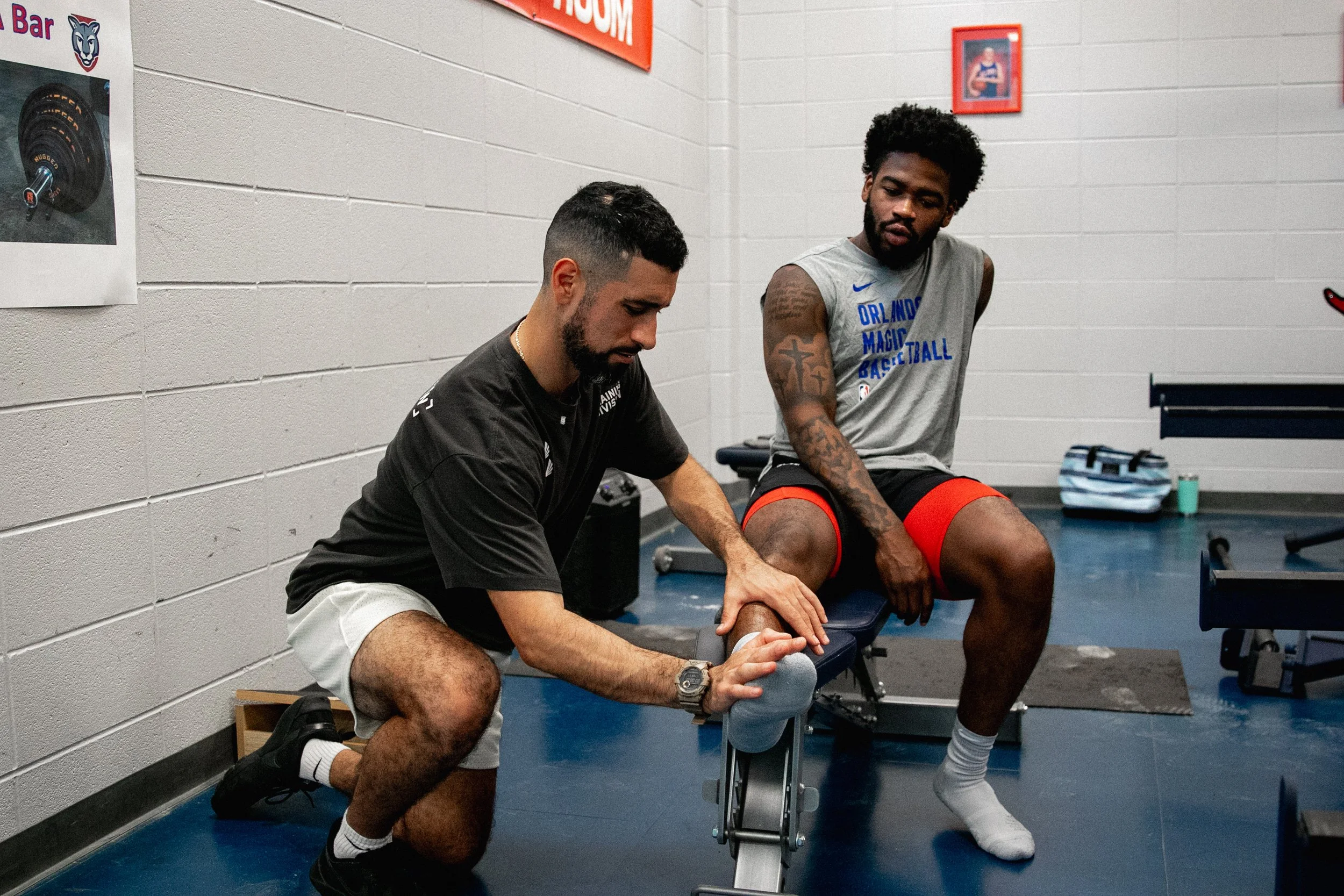 Cristian working on Jamal Shead's foot and ankle in a training room while he wears an Orlando Magic shirt