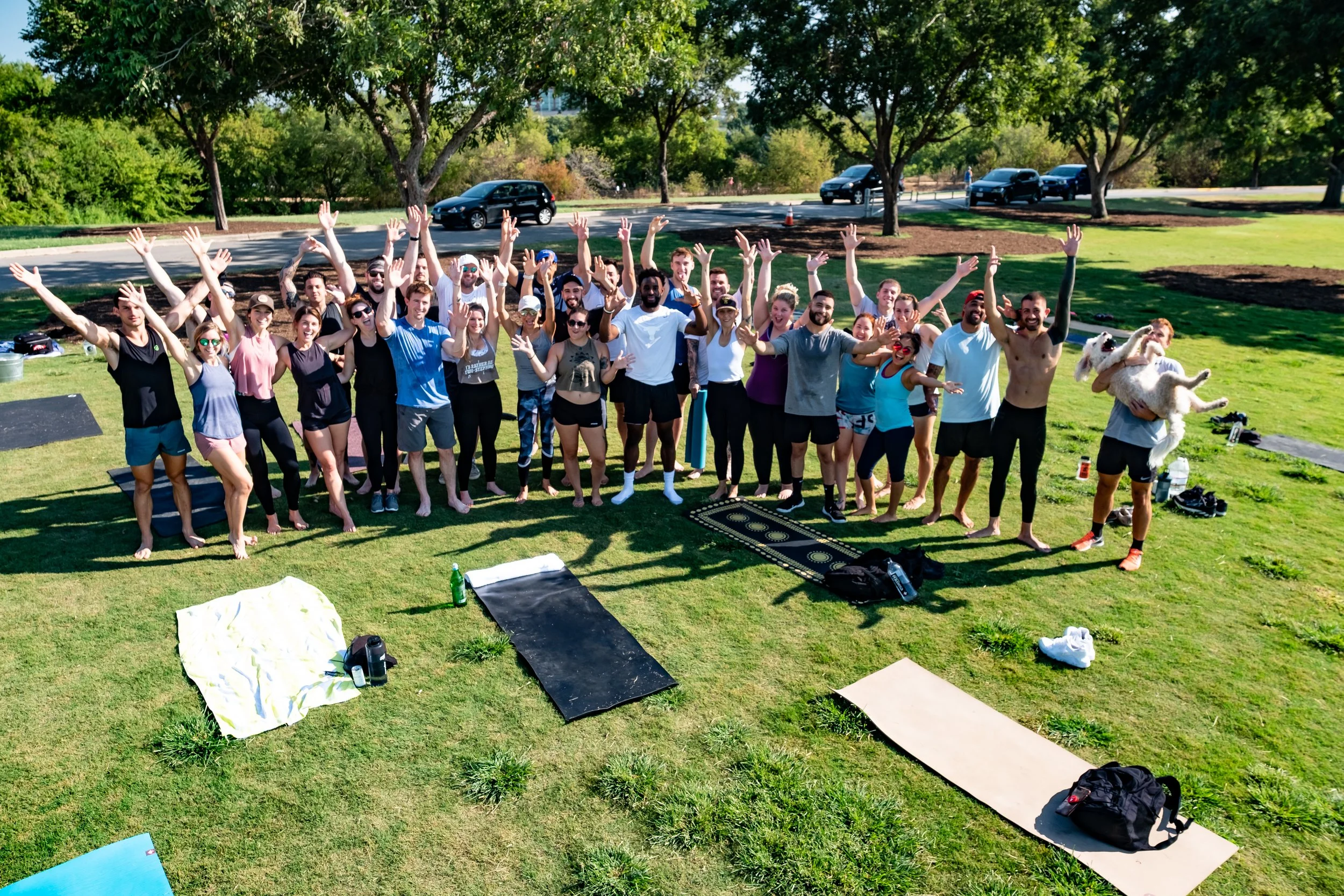 A large group of athletes raising their hands in an Austin park after an outdoor Durable Athlete session