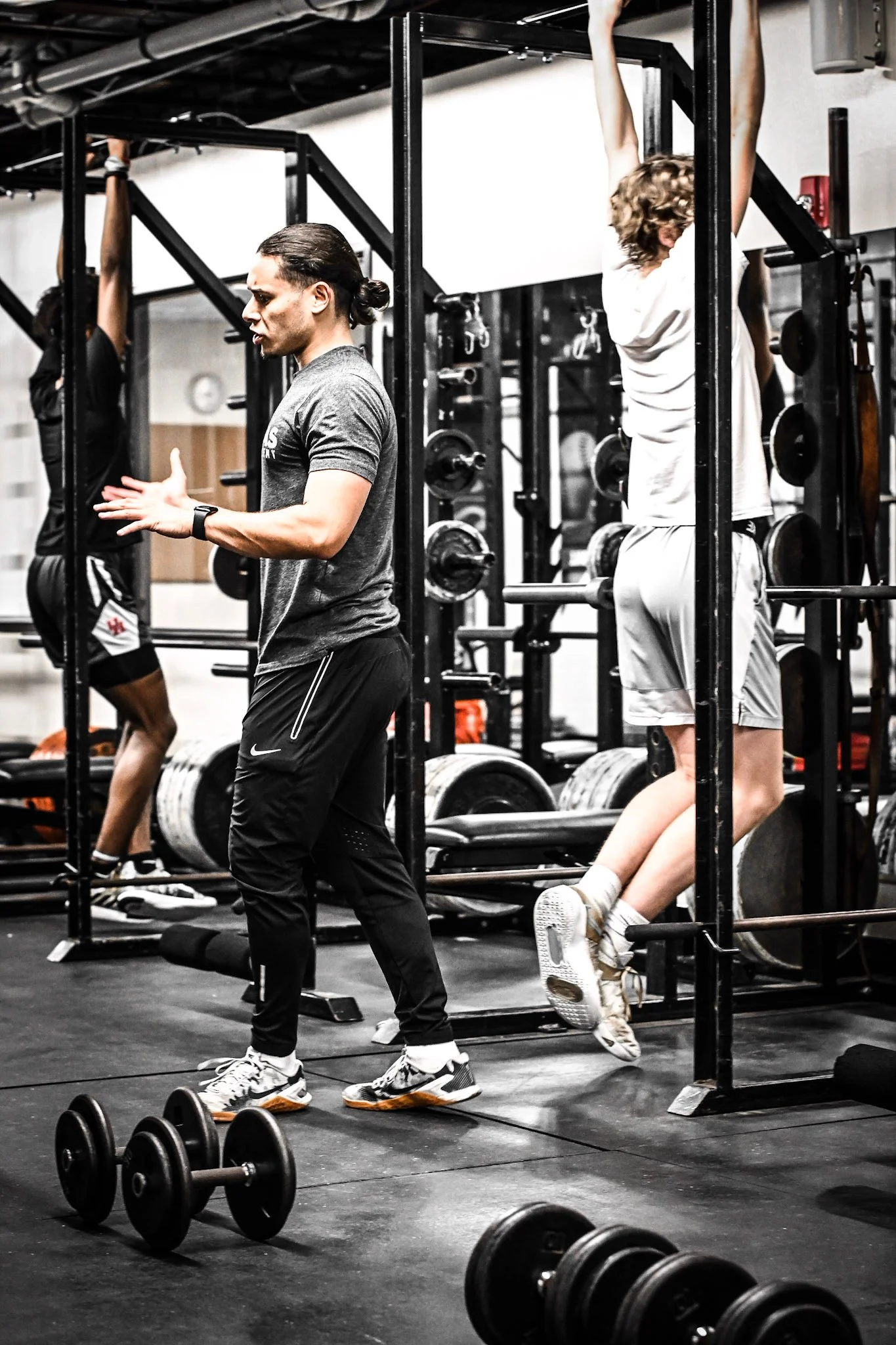 Jose Diaz directing athletes at a pull-up rig in a black-and-white gym photo