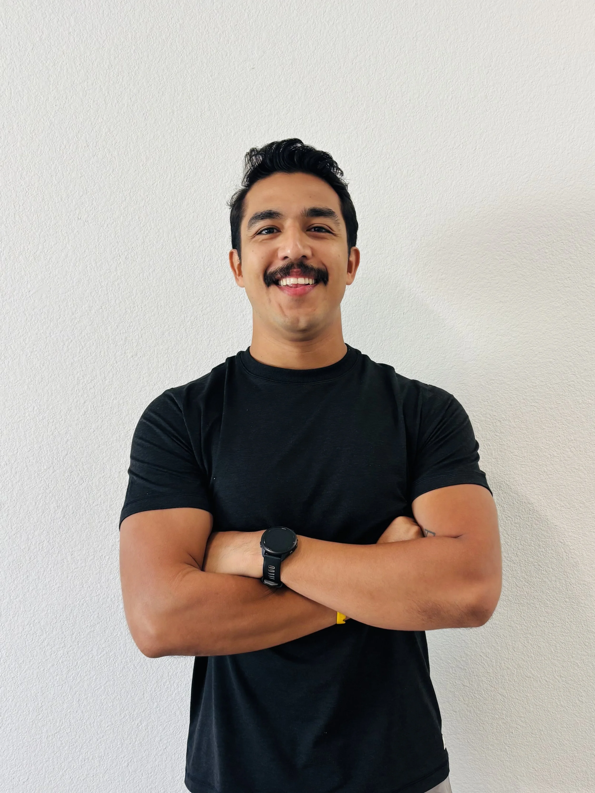 Daniel Guerrero with arms crossed in a black tee against a light wall