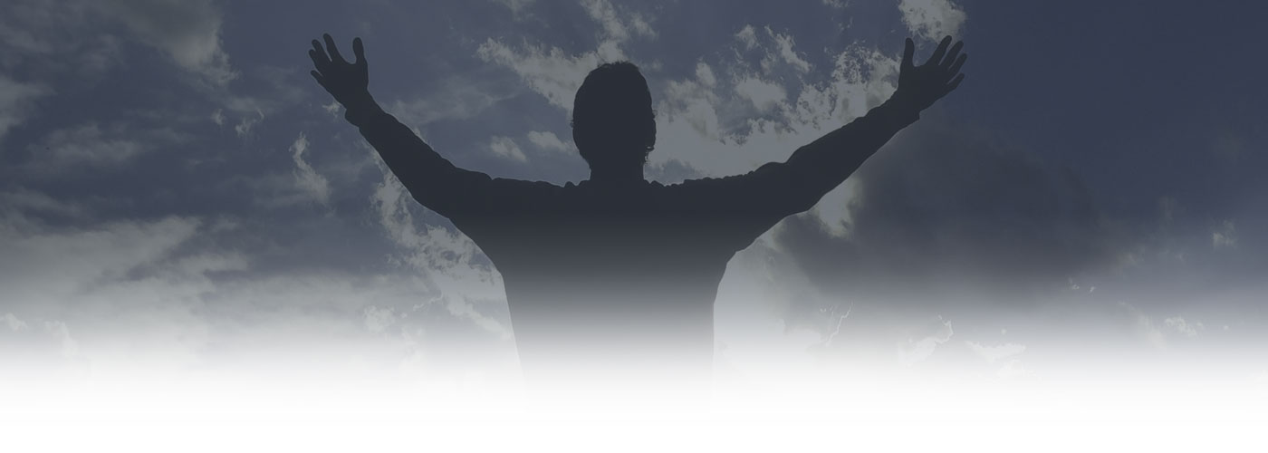 Silhouette of a person with arms raised wide against a dramatic cloudy sky