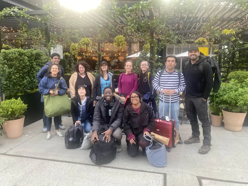 Early Burdz getaway group posing with luggage under a string-lit outdoor pergola