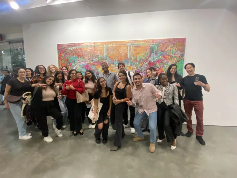 Large group of Early Burdz guests posing in front of a big colorful painting during a gallery hop