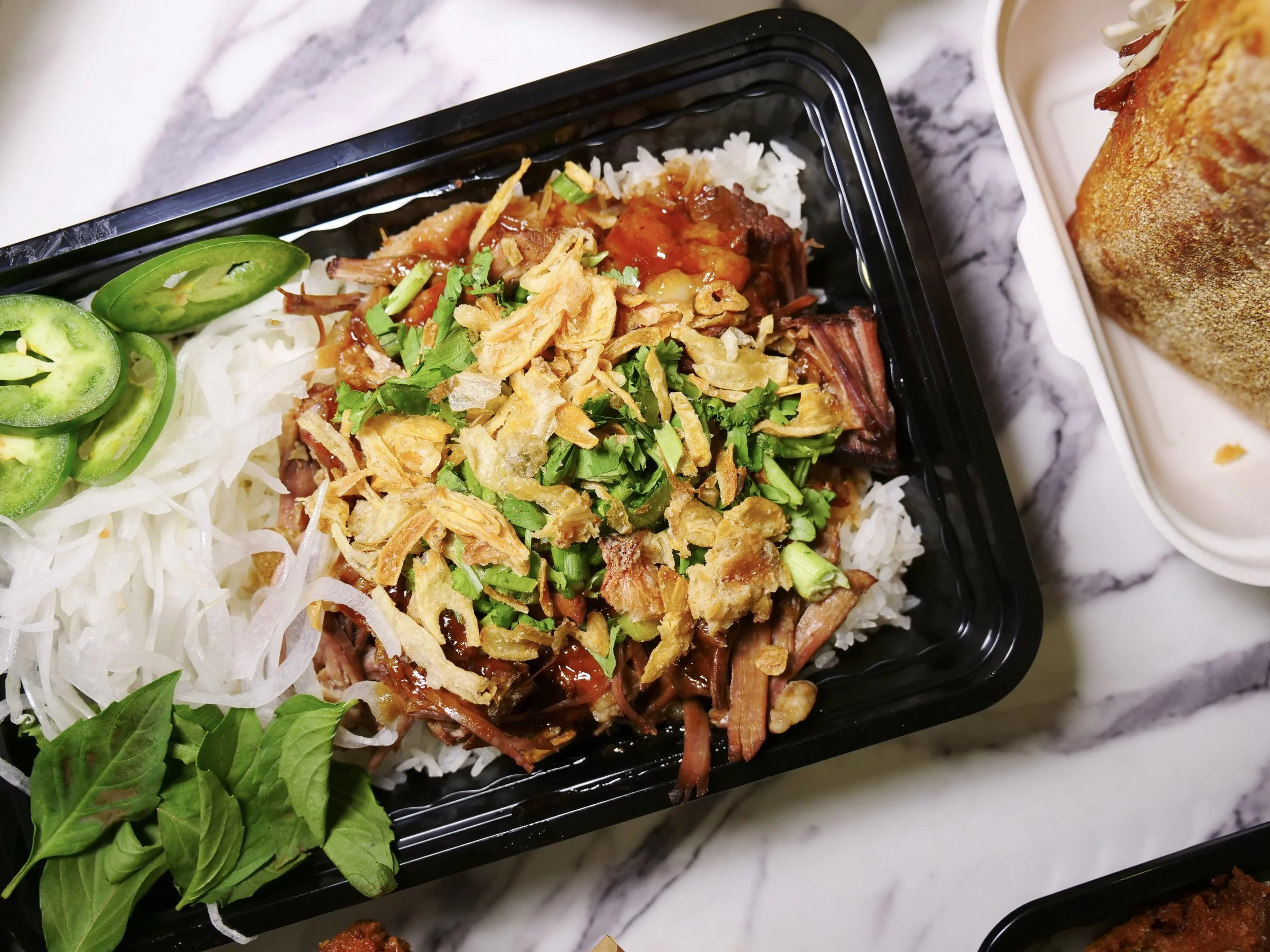 Braised pork rice bowl with cilantro, fried shallots, jalapeños and fresh herbs