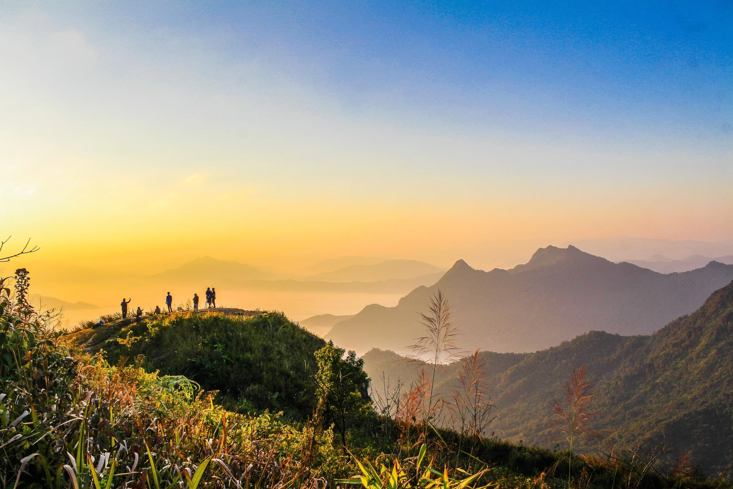 Silhouetted figures on a mountain ridge at sunrise