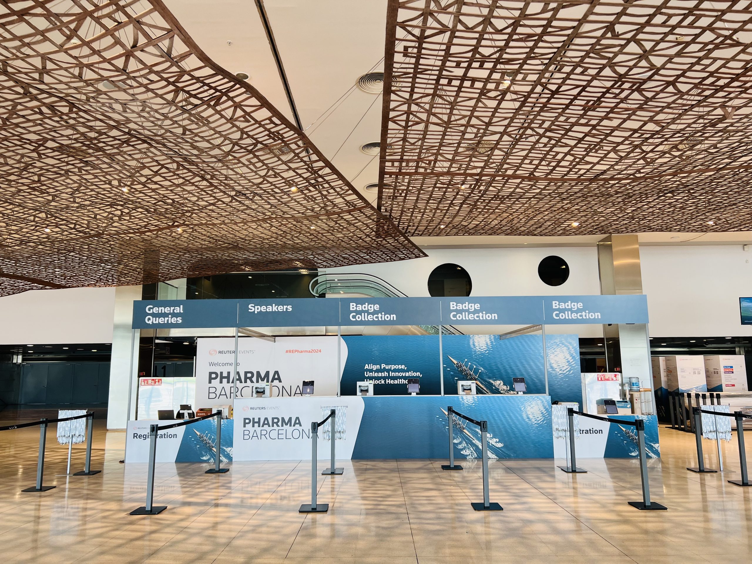 Reuters Events Pharma Barcelona registration hall with badge collection counters and lattice ceiling