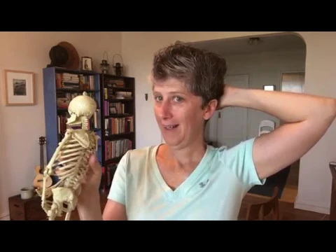 Clare Maxwell holding a model skeleton while teaching in a home setting