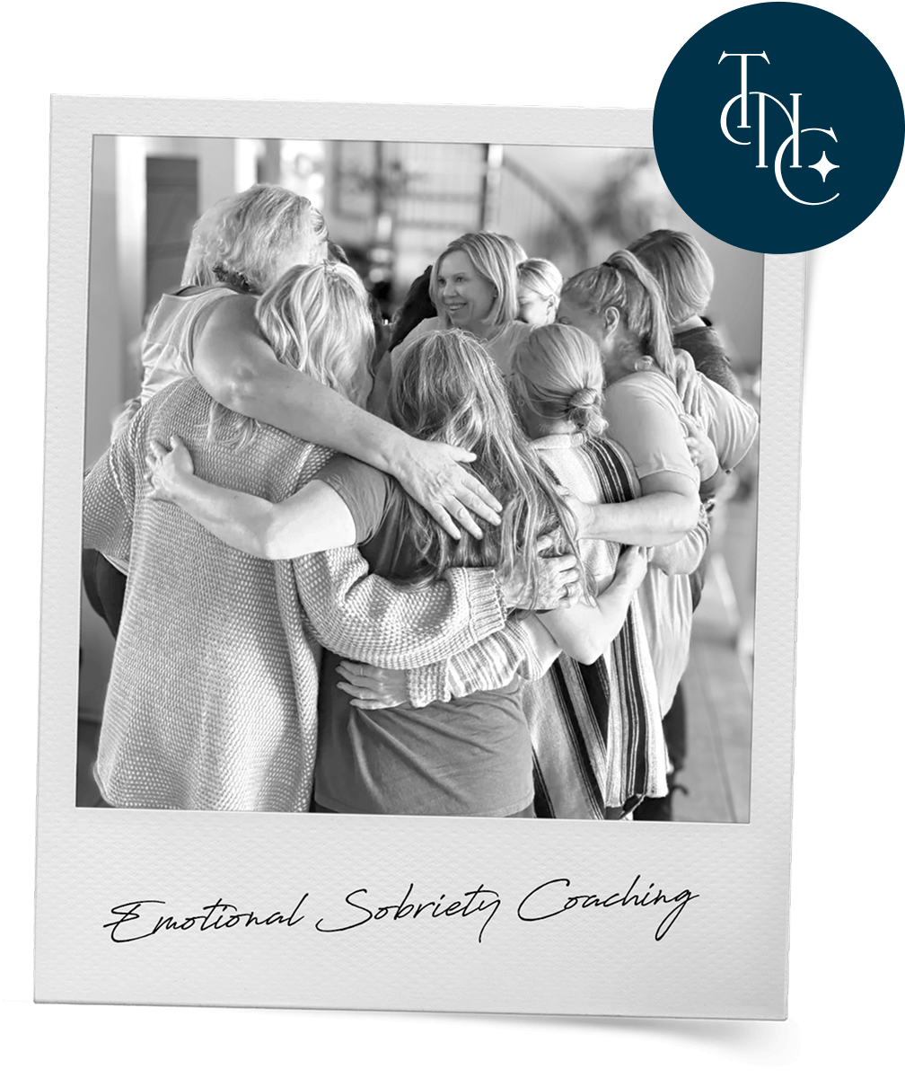 Black-and-white polaroid of a group of women in a group hug, stamped with The Next Chapter badge