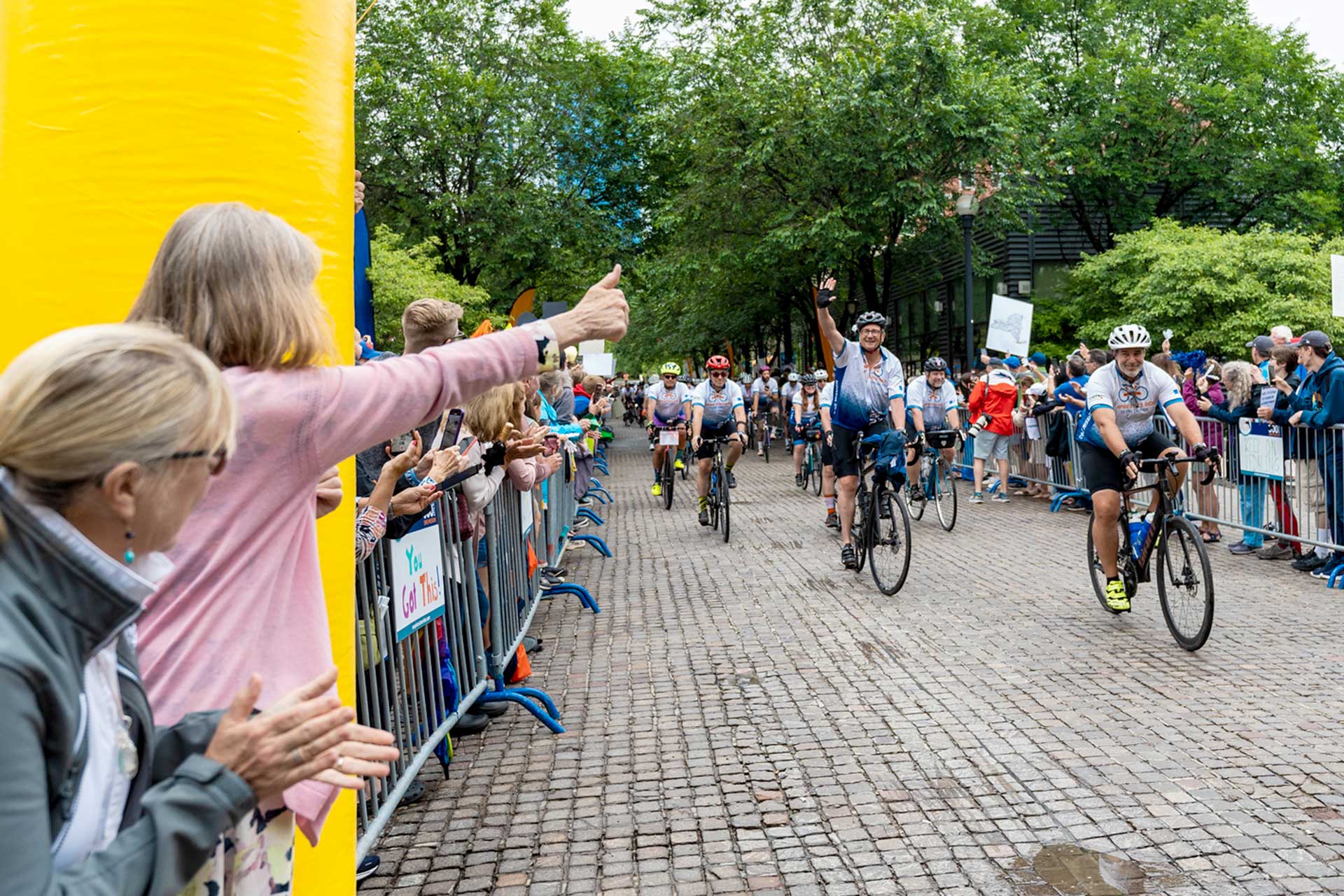 Cyclists arriving at a finish line cheered by spectators