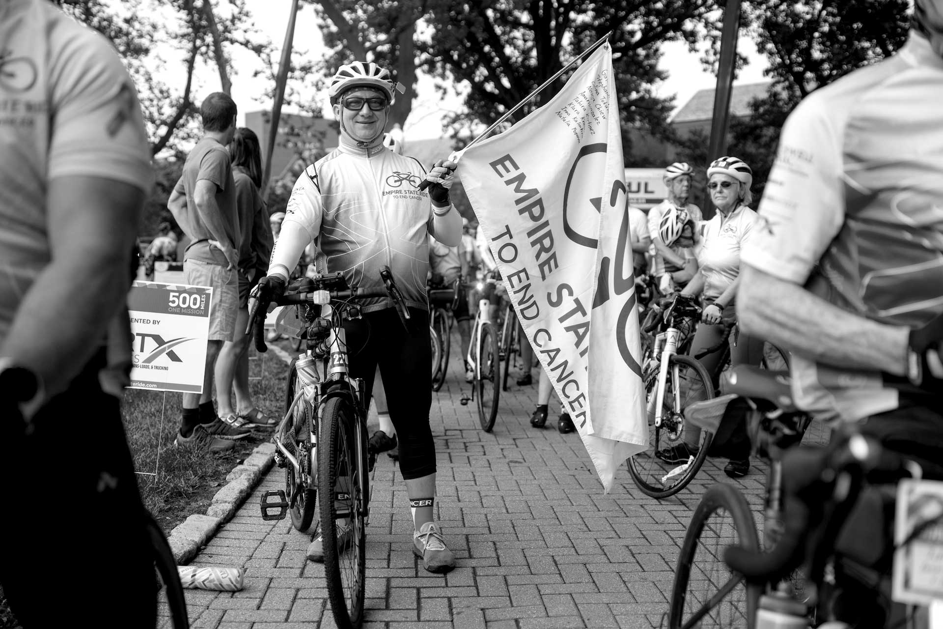 Cyclist carrying an Empire State Ride flag at the event start