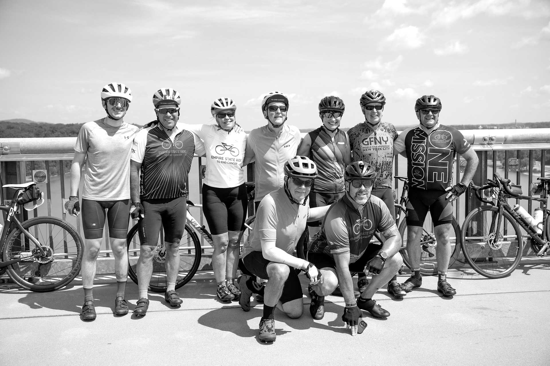Group of cyclists posing on a bridge over a river