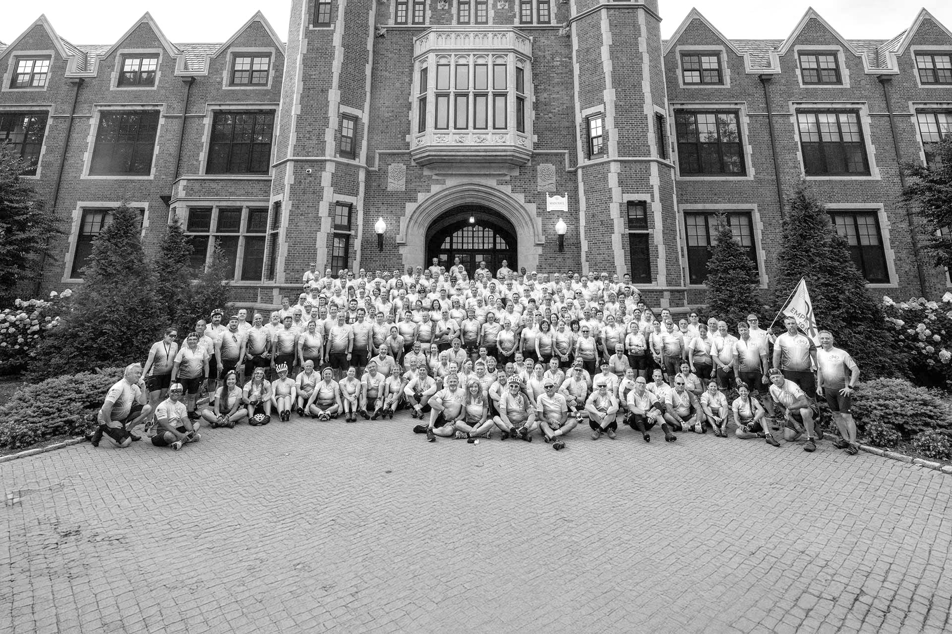 Large group photo of cyclists in front of a brick building