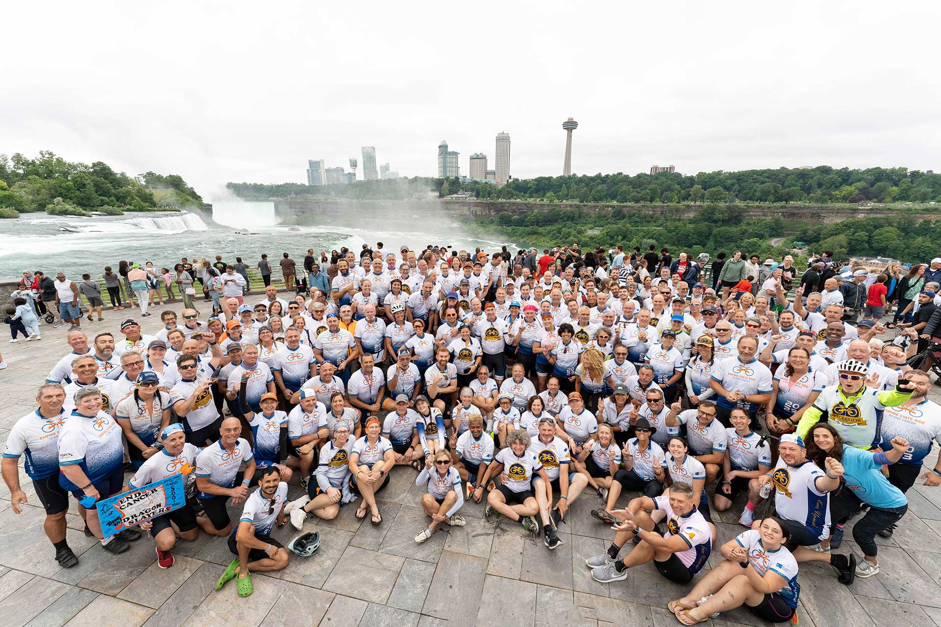 Hundreds of cyclists in white and blue Empire State Ride jerseys at the Niagara Falls overlook