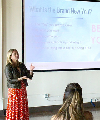 Michelle in a red dress presenting 'What is the Brand New You?' at a workshop