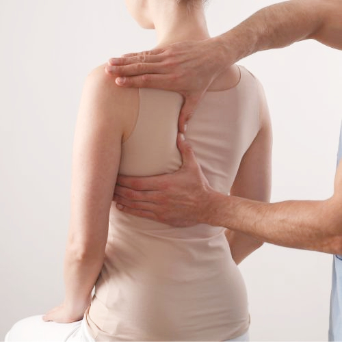 Practitioner assessing a seated patient's posture from behind