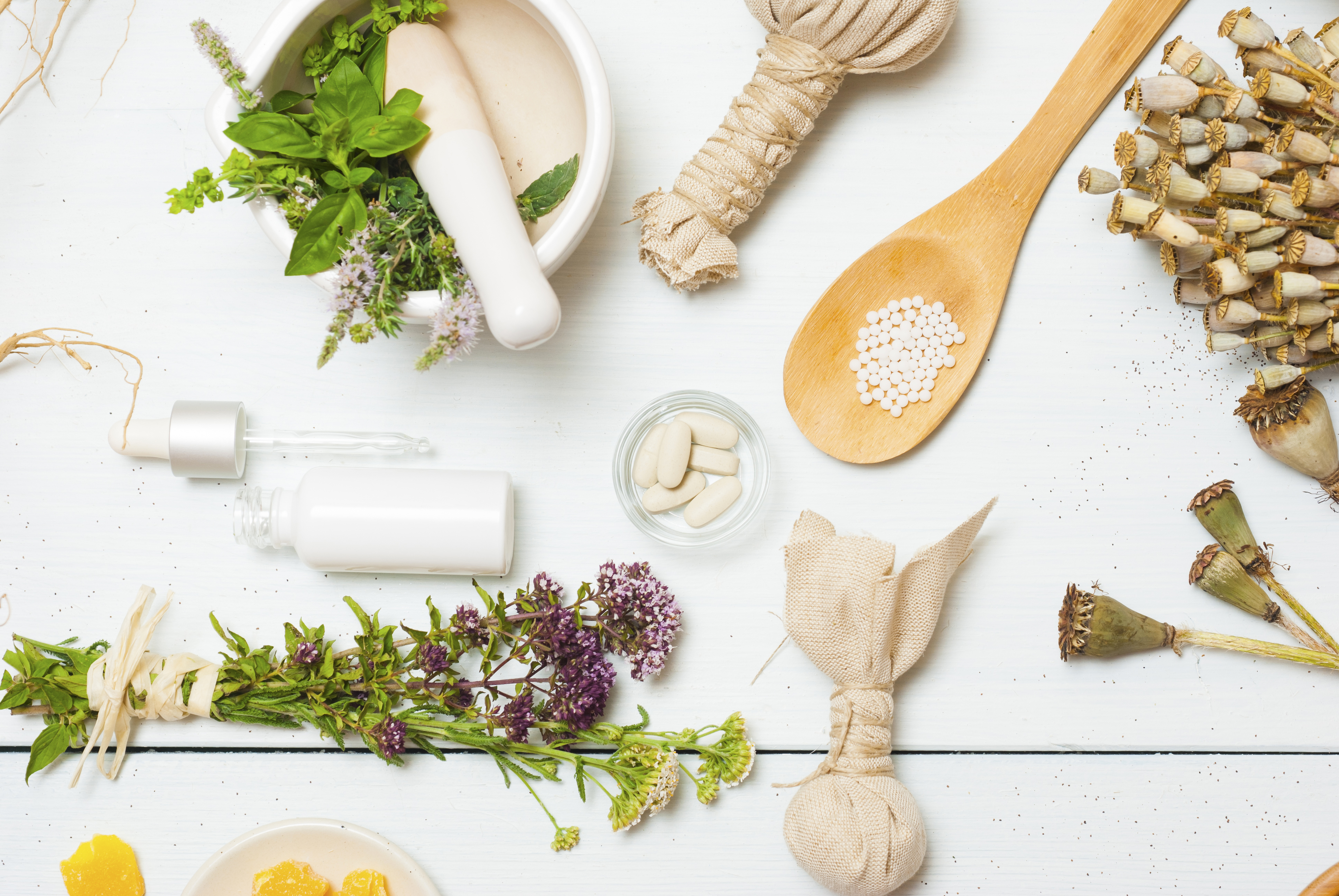 Flat-lay of herbal medicine: mortar and pestle, dried flowers, sachets and glass bottle