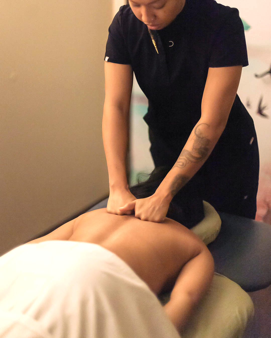 Massage therapist treating a client lying prone on a treatment table