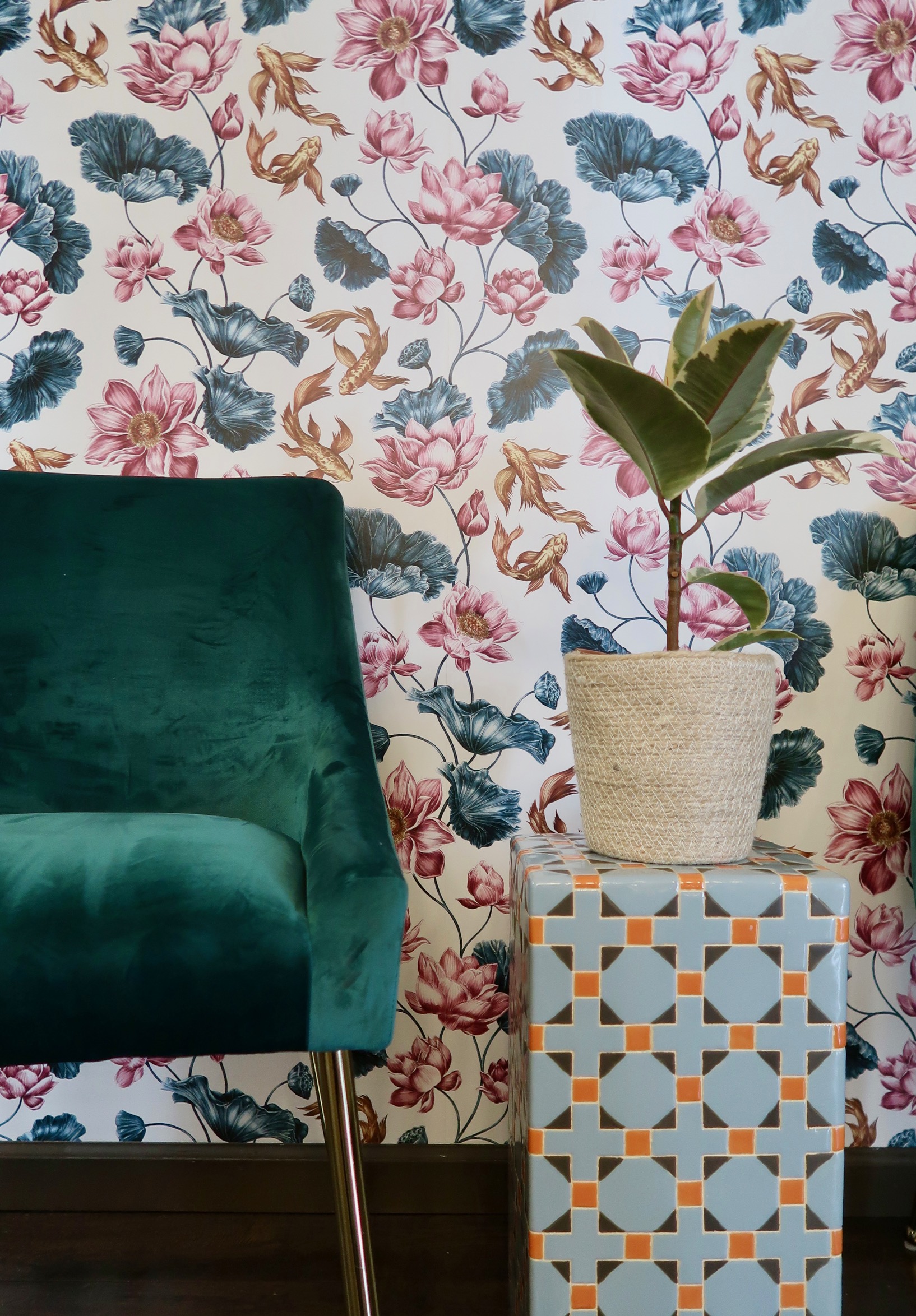 Encore waiting area with a teal velvet chair, koi-print wallpaper and a potted plant