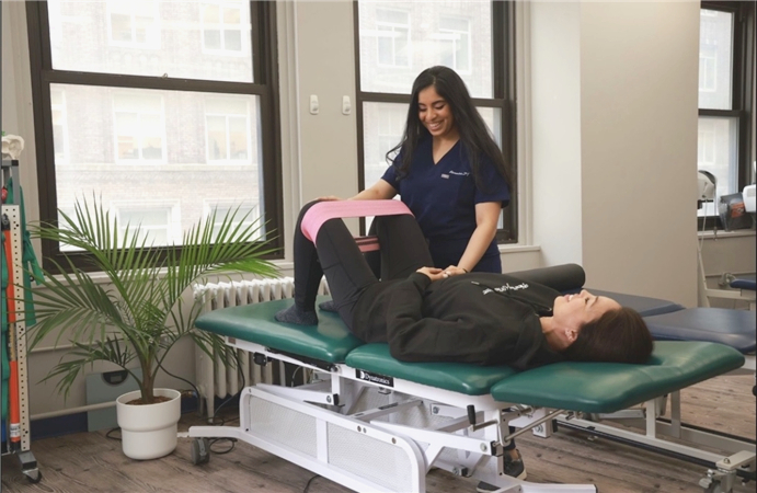 Physical therapist assisting a patient with a resistance band leg exercise