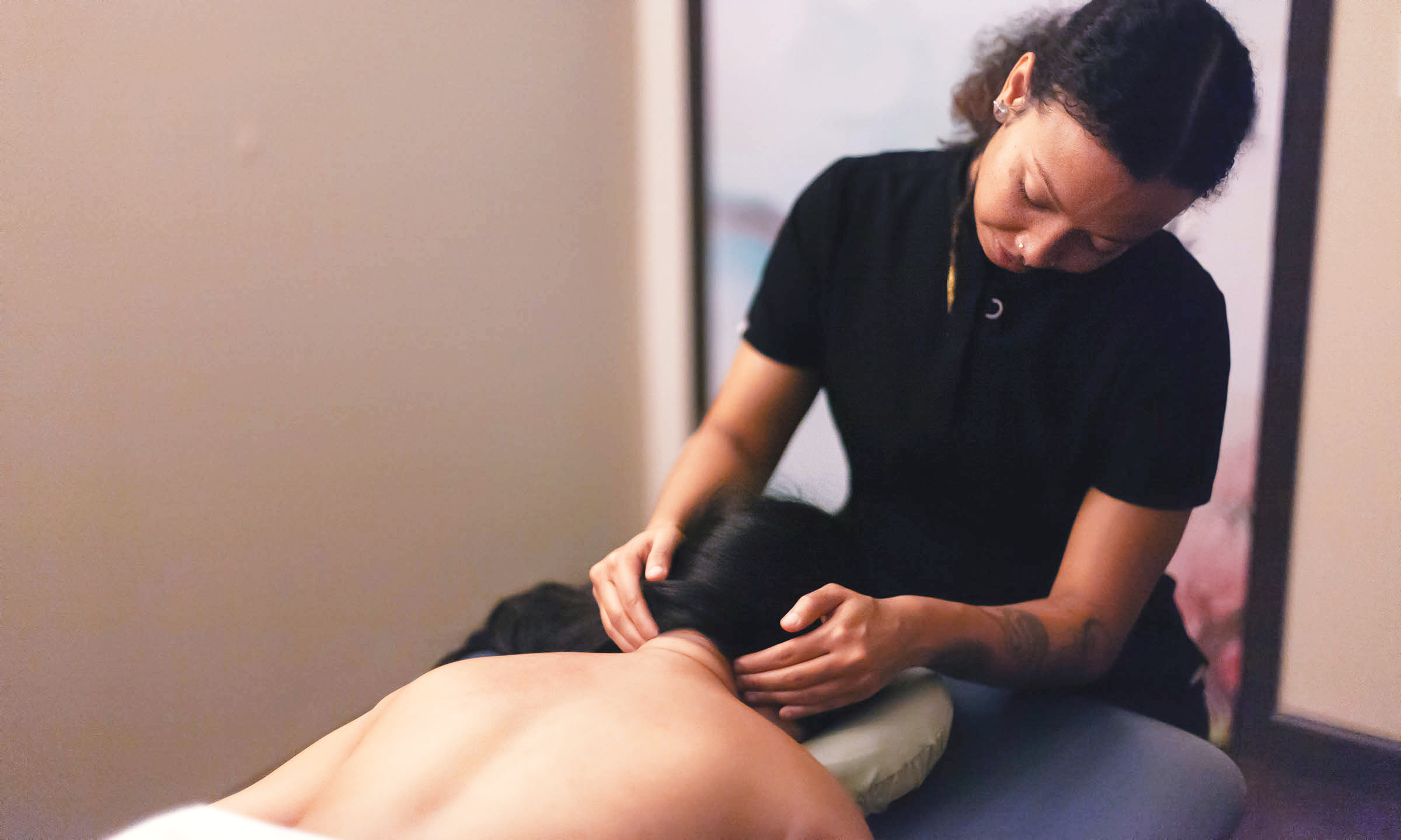 Massage therapist working on a client's upper back and shoulder