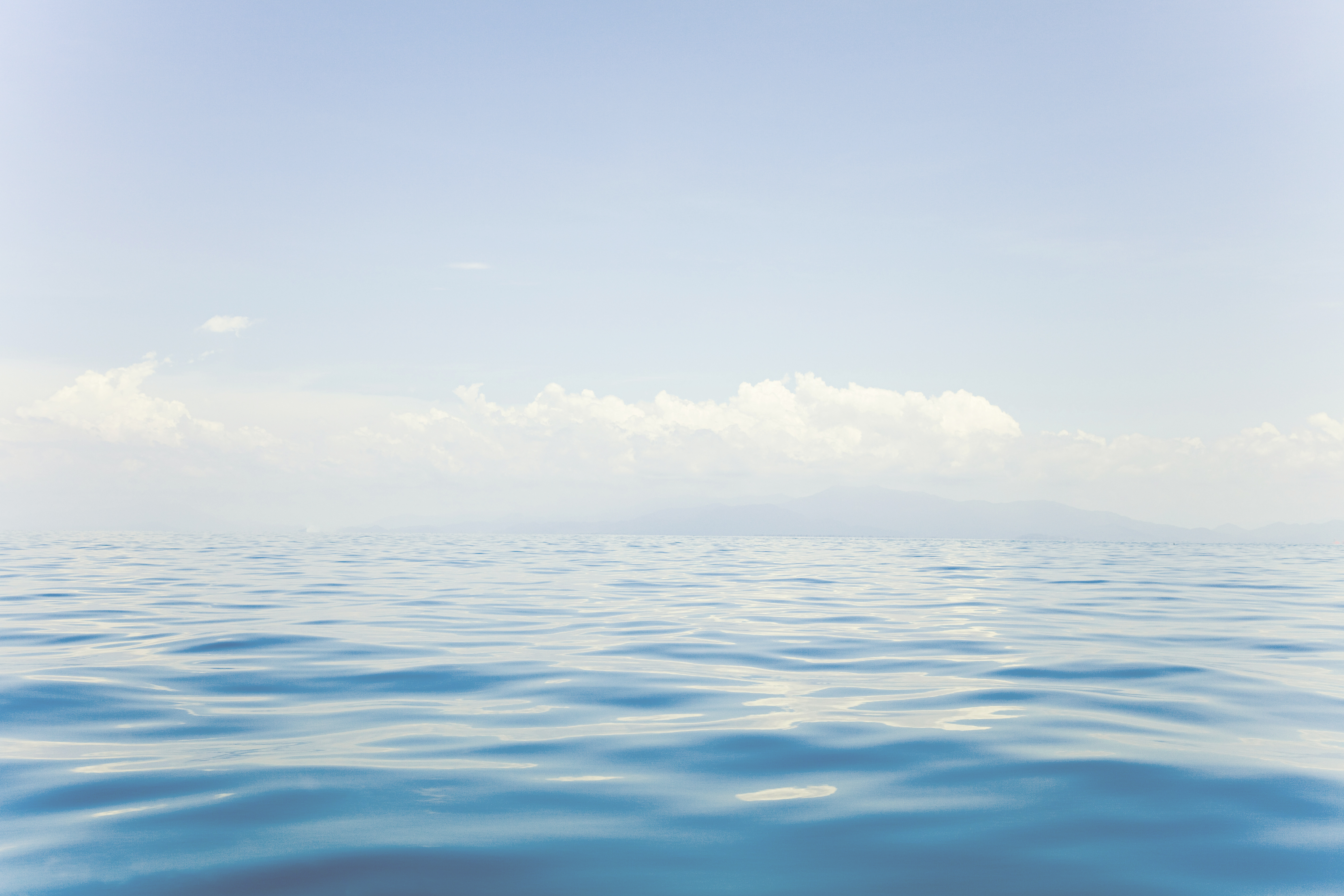 Calm ocean surface under a soft blue sky