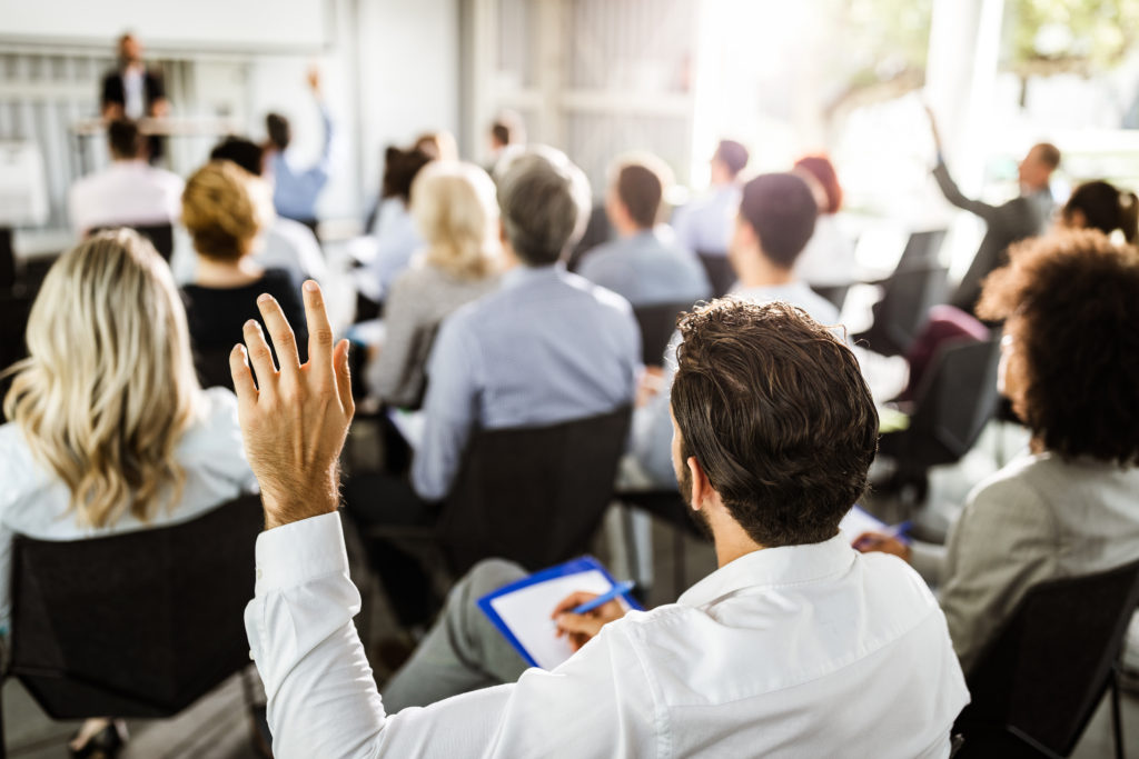 Training seminar audience raising hands toward a presenter