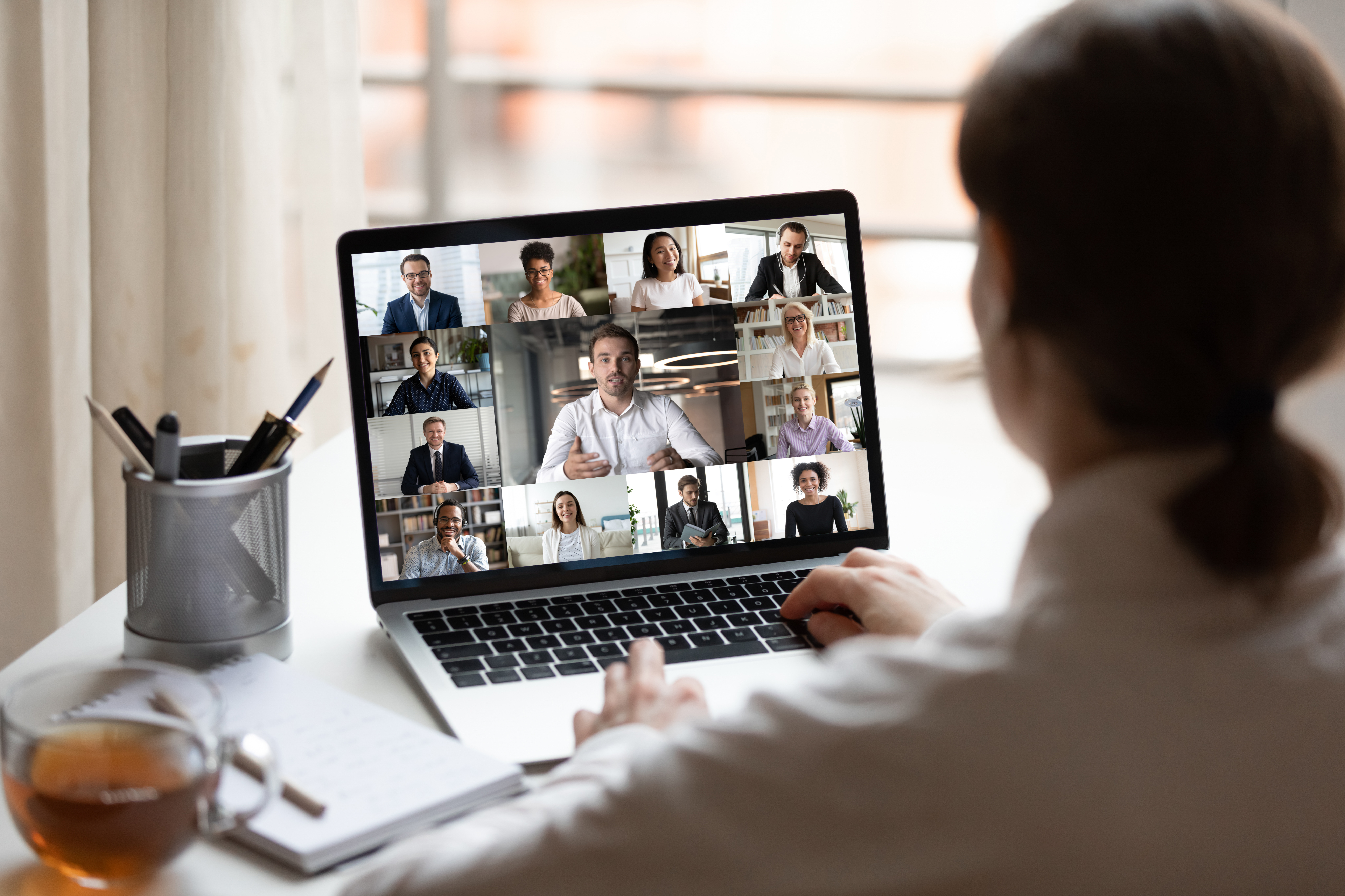 Woman on a laptop video call with multiple participants on screen