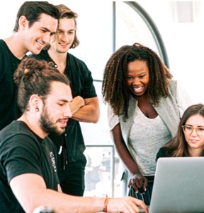 Group of four professionals gathered around a laptop, smiling
