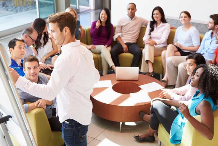 Man presenting to a diverse group in a casual lounge meeting room