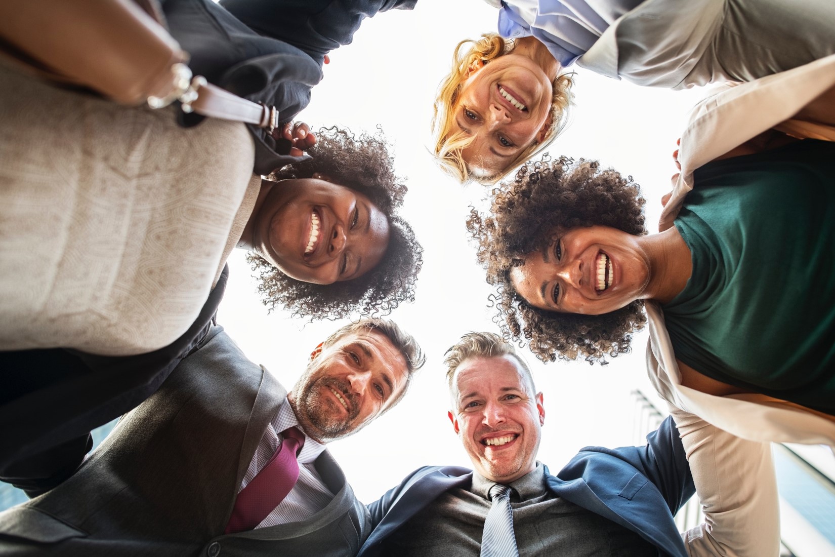 Diverse team of professionals in a huddle viewed from below