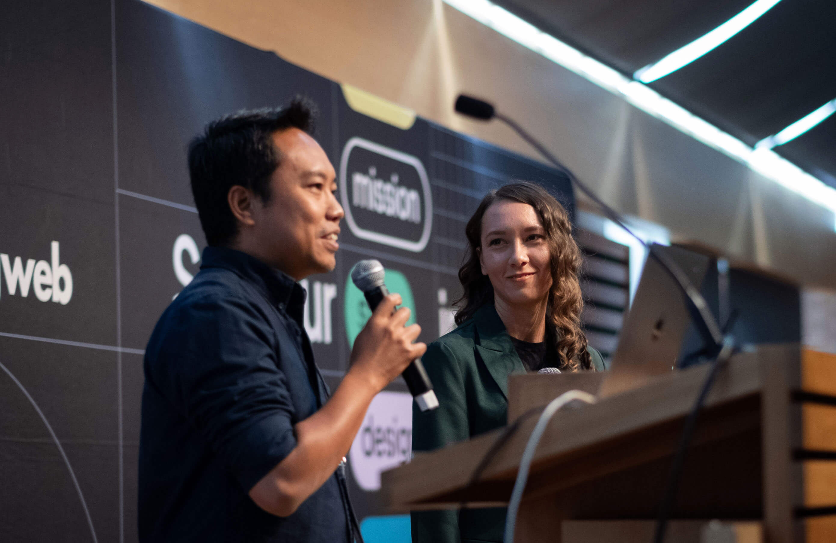 Two speakers on stage in front of an evolvingweb backdrop