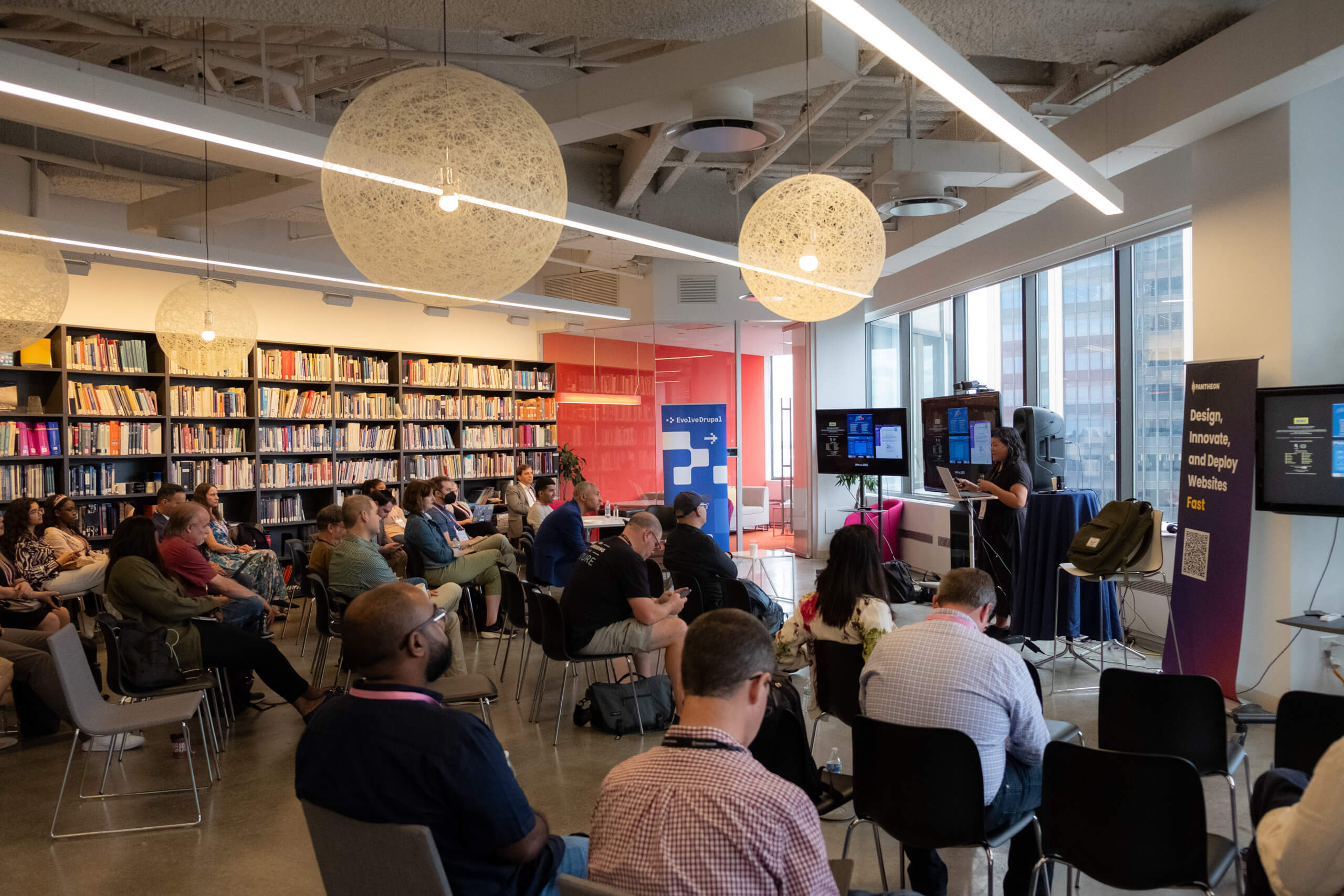 Speaker presenting to a seated audience in a library-style room at EvolveDigital NYC