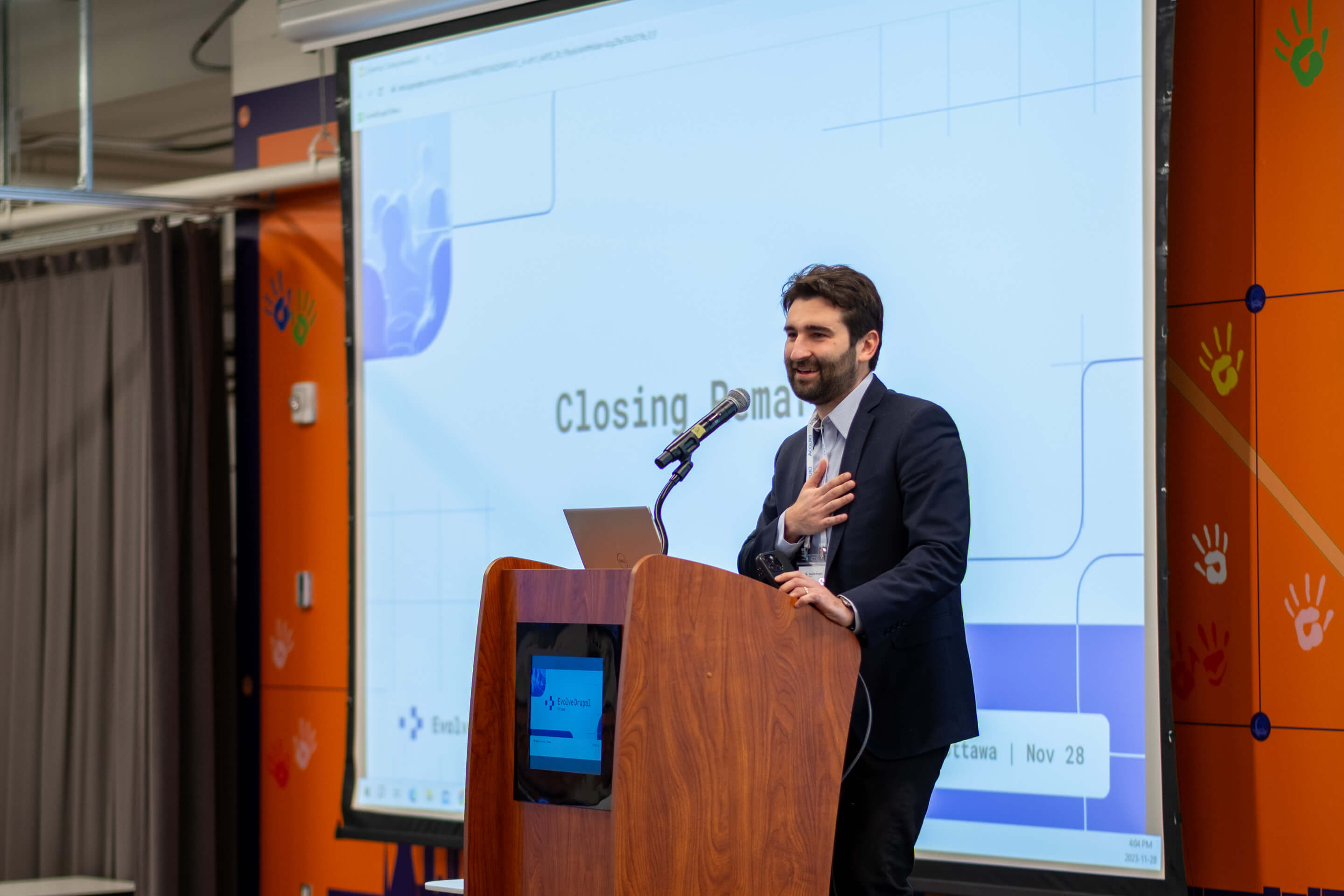 Speaker delivering closing remarks at the podium during EvolveDrupal Ottawa