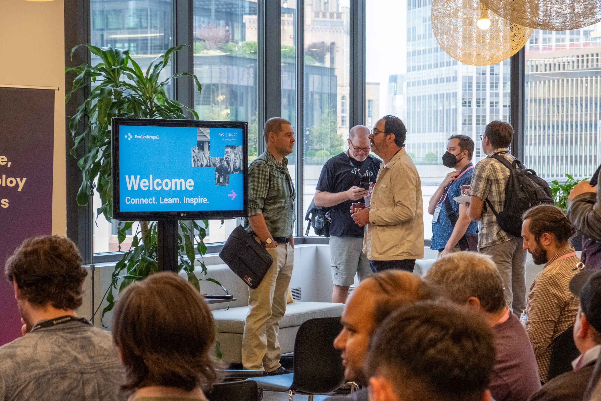 Attendees networking at EvolveDigital NYC with the city skyline through the windows