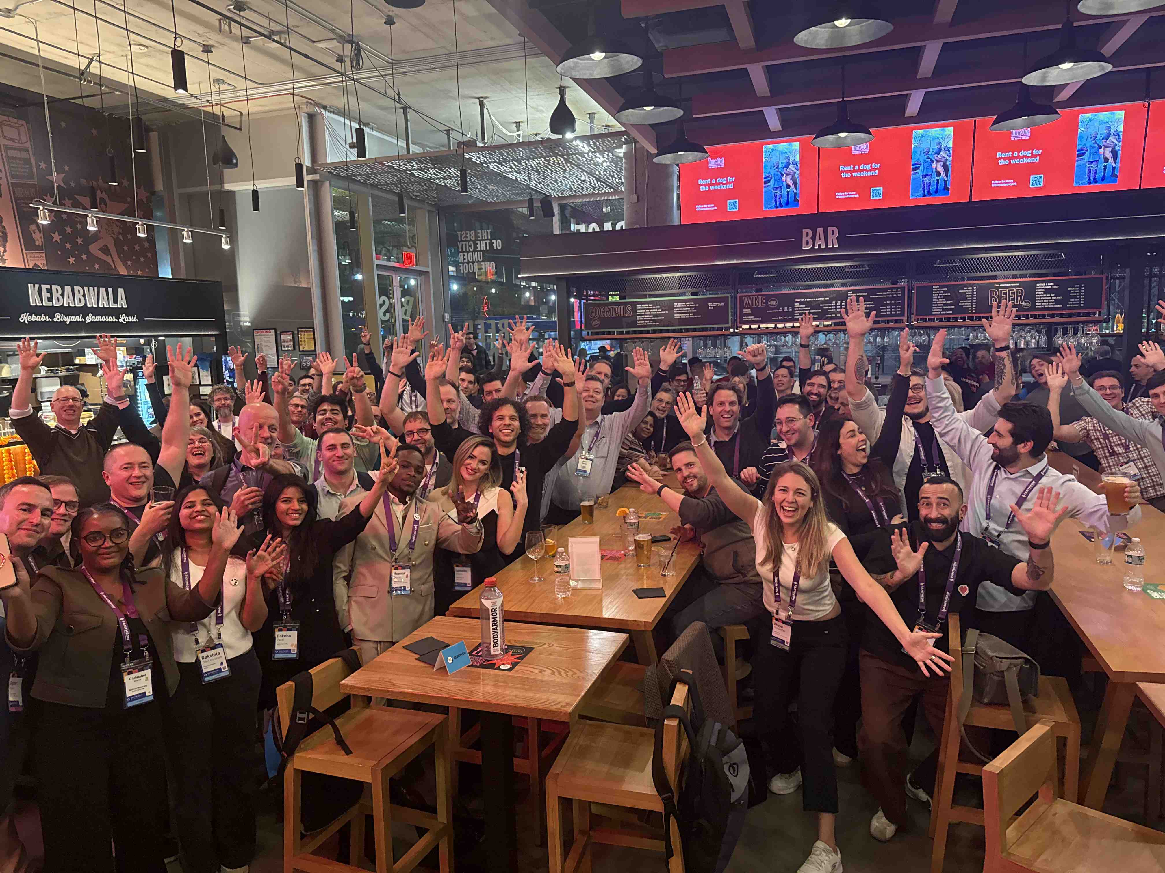 Large group of EvolveDigital attendees cheering with hands raised at the evening social