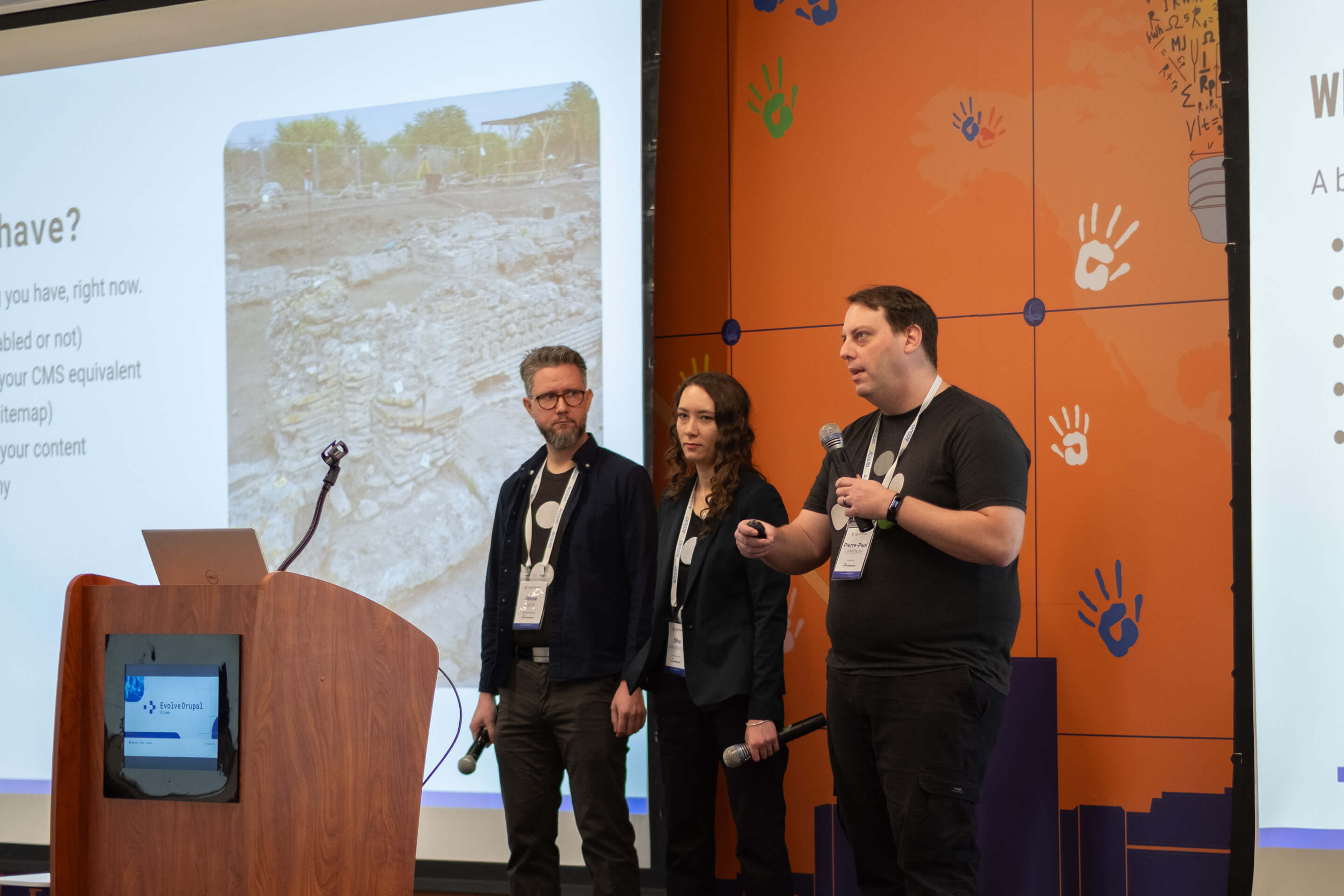 Three co-presenters speaking together on stage at EvolveDrupal Ottawa