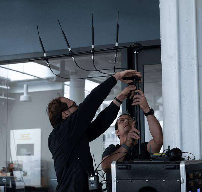 Two Eyes Up technicians rigging a wireless antenna array before a show.