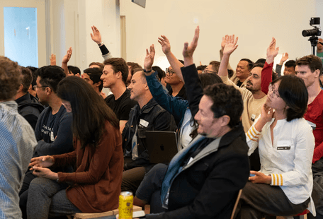 Audience members raising hands during a small event.