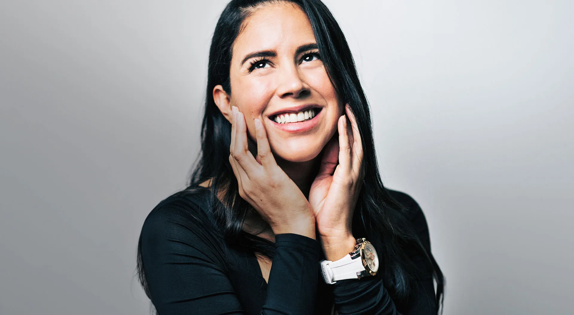 Patient laughing with hands on her cheeks after an Invisalign smile makeover in Union Square, Manhattan