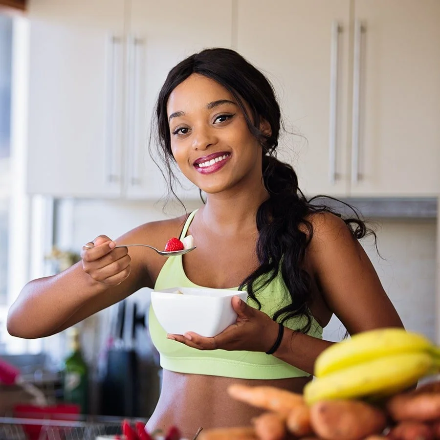 Woman eating a fruit bowl in a kitchen