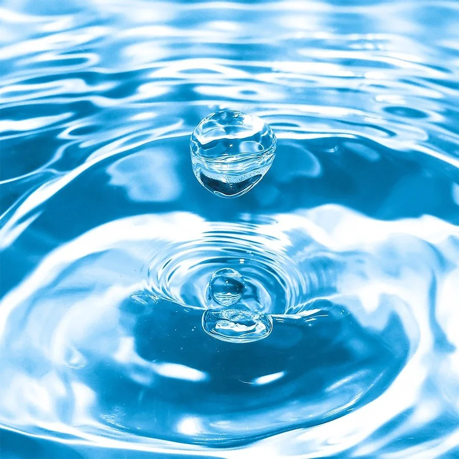 Water droplet creating ripple rings on a blue water surface