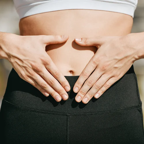 Close-up of hands resting on a stomach during colon hydrotherapy