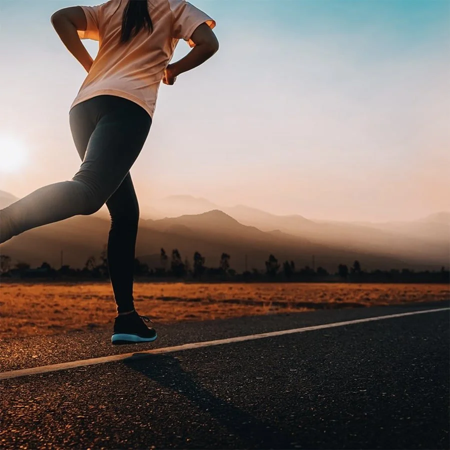 Woman running on a road at sunset