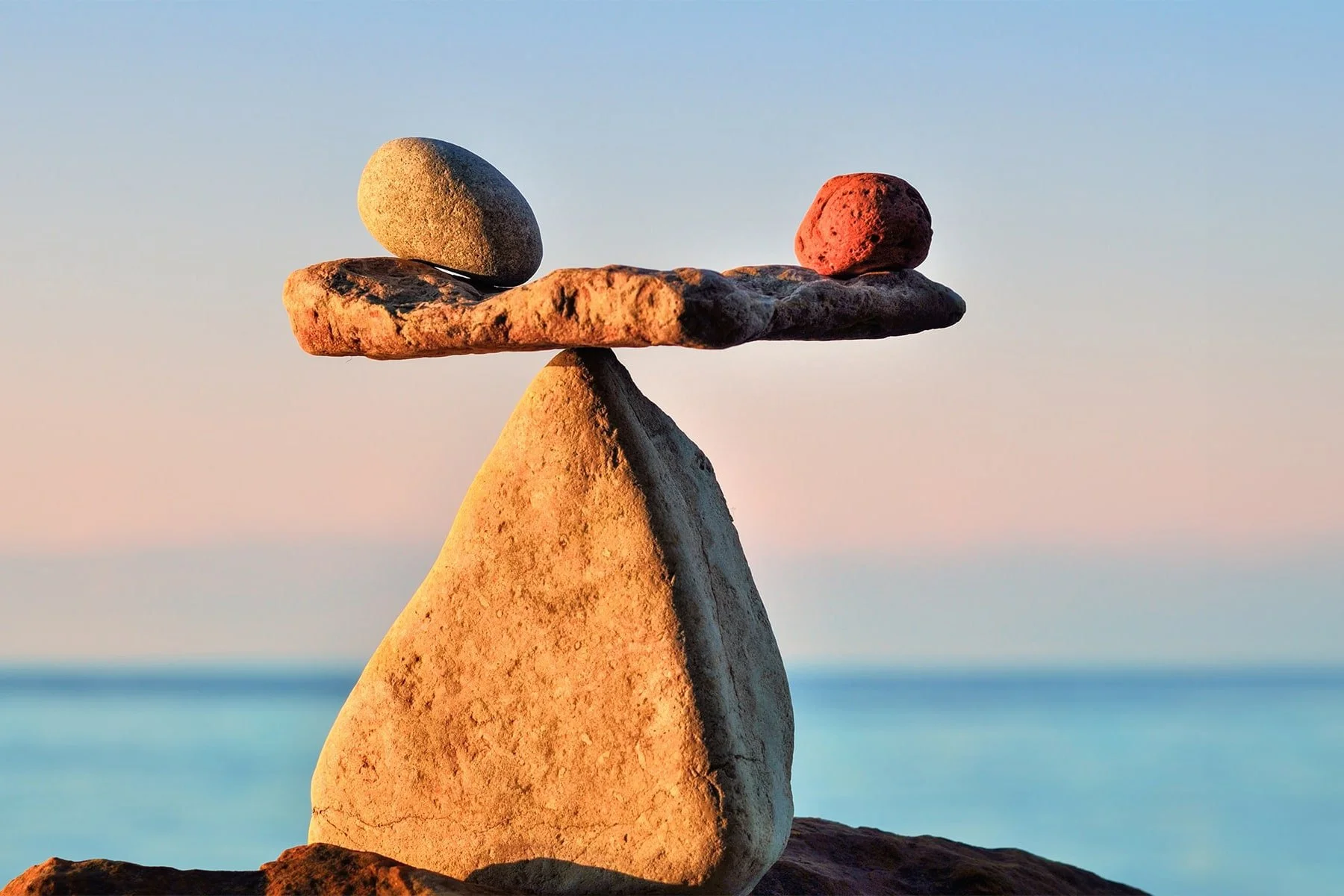 Balanced stacked rocks at sunset over the ocean