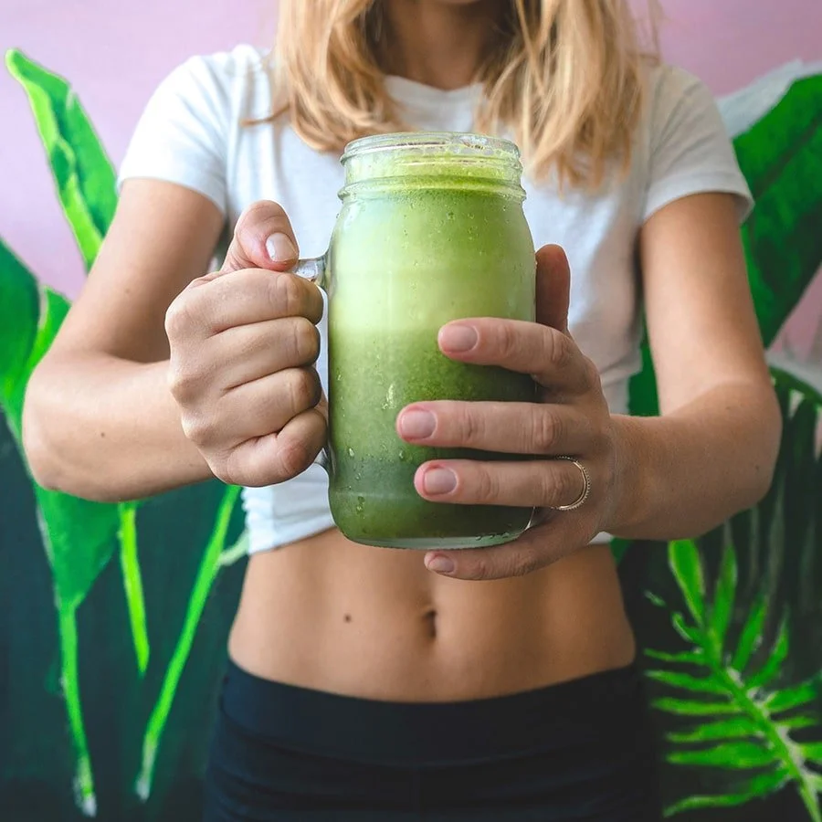 Woman holding a jar of green juice