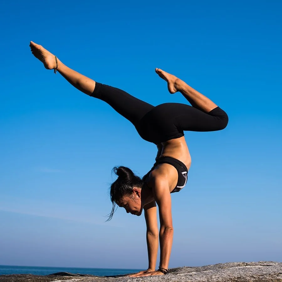 Woman doing a handstand split on a rocky outcrop